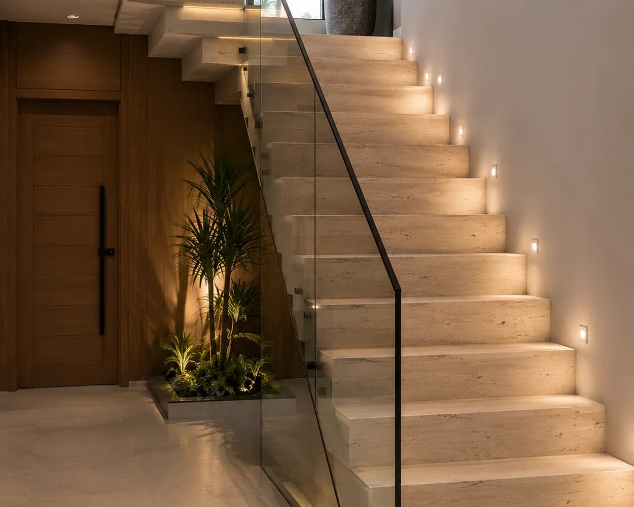 Escada em pedra natural clara com guarda-corpo de vidro e iluminação embutida nos degraus